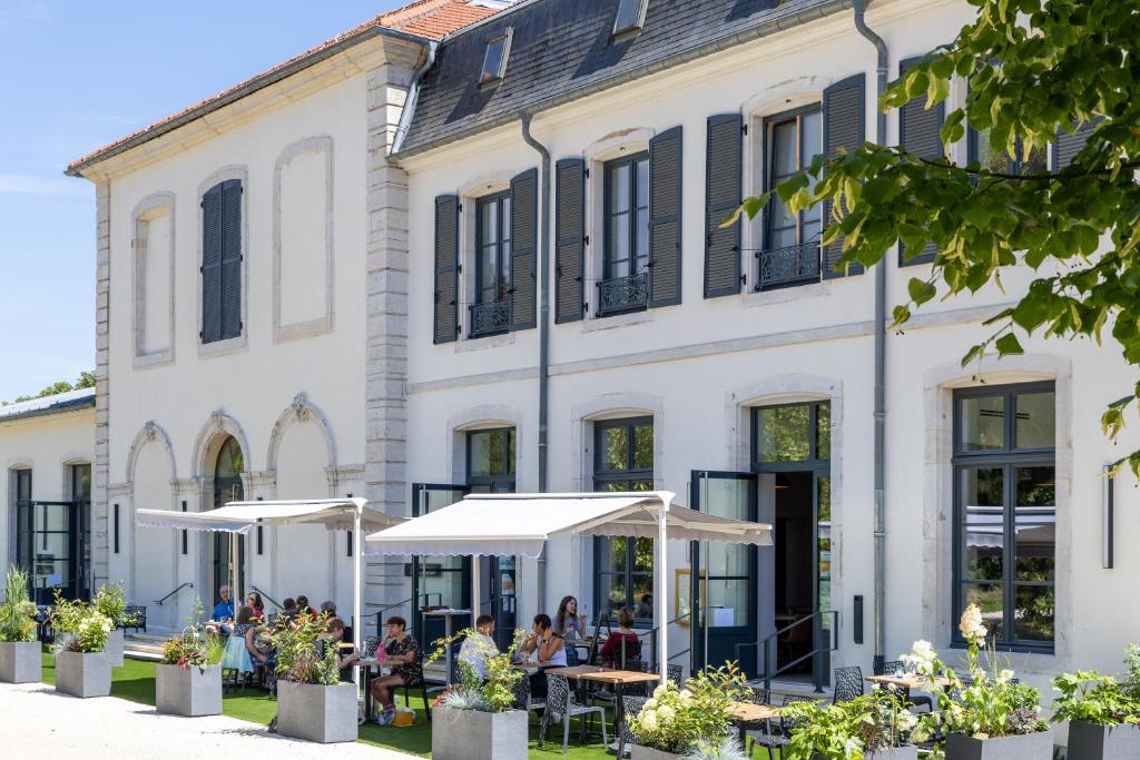 a building with tables and umbrellas in front of it at Hôtel du Château in Villers-lès-Nancy