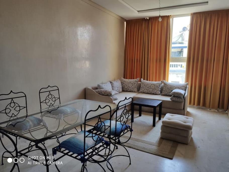 uma sala de estar com uma mesa de vidro e um sofá em Appart ensoleillé prés du port! em Casablanca
