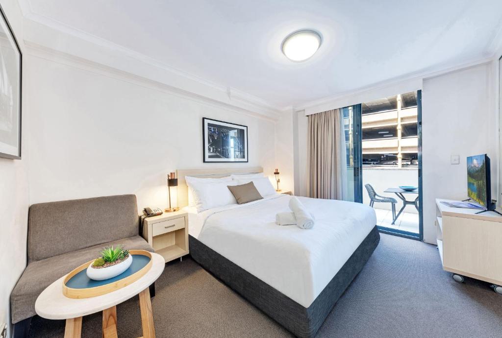 a bedroom with a bed and a couch and a table at Modern and Cosy Sydney CBD Studio in Central in Sydney