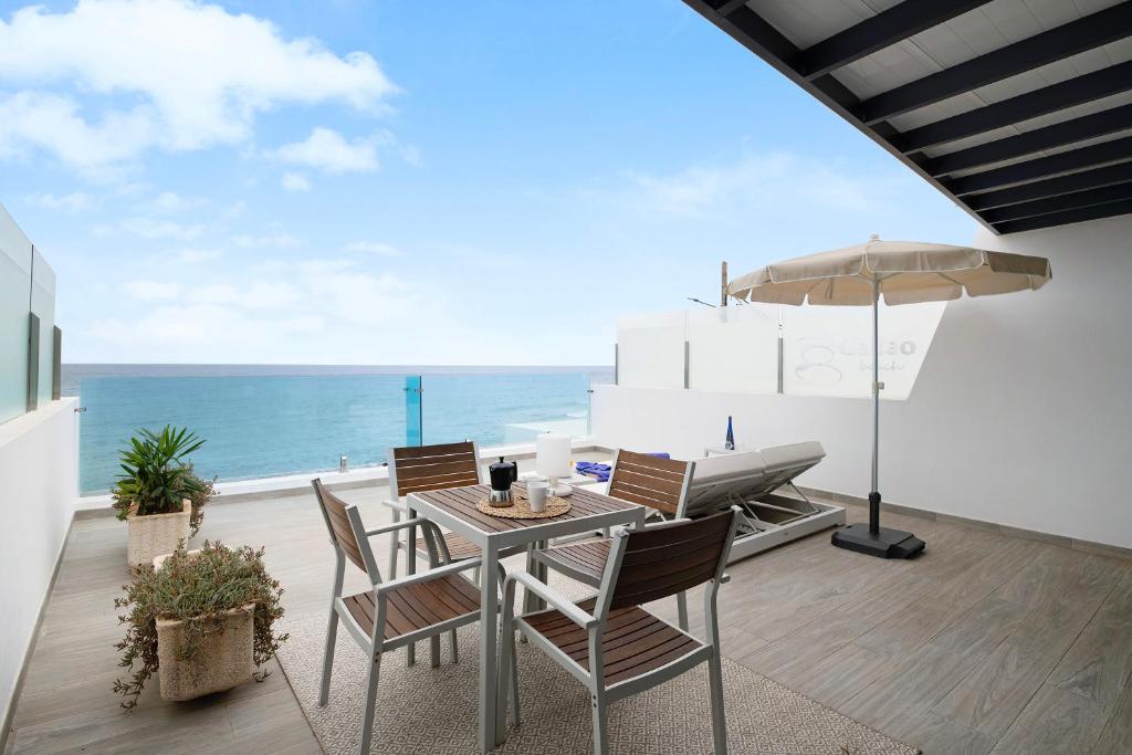 eine Terrasse mit einem Tisch, Stühlen und Meerblick in der Unterkunft Callao Beach 8 in Arrieta