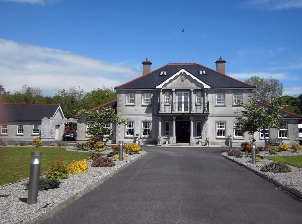 
a large white house with a large clock on the front of it at Deerpark Manor Bed and Breakfast in Swinford
