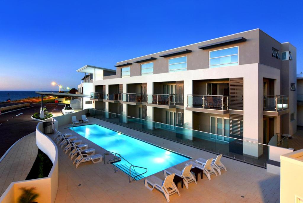 a building with a swimming pool and chairs at Bunbury Seaview Apartments in Bunbury