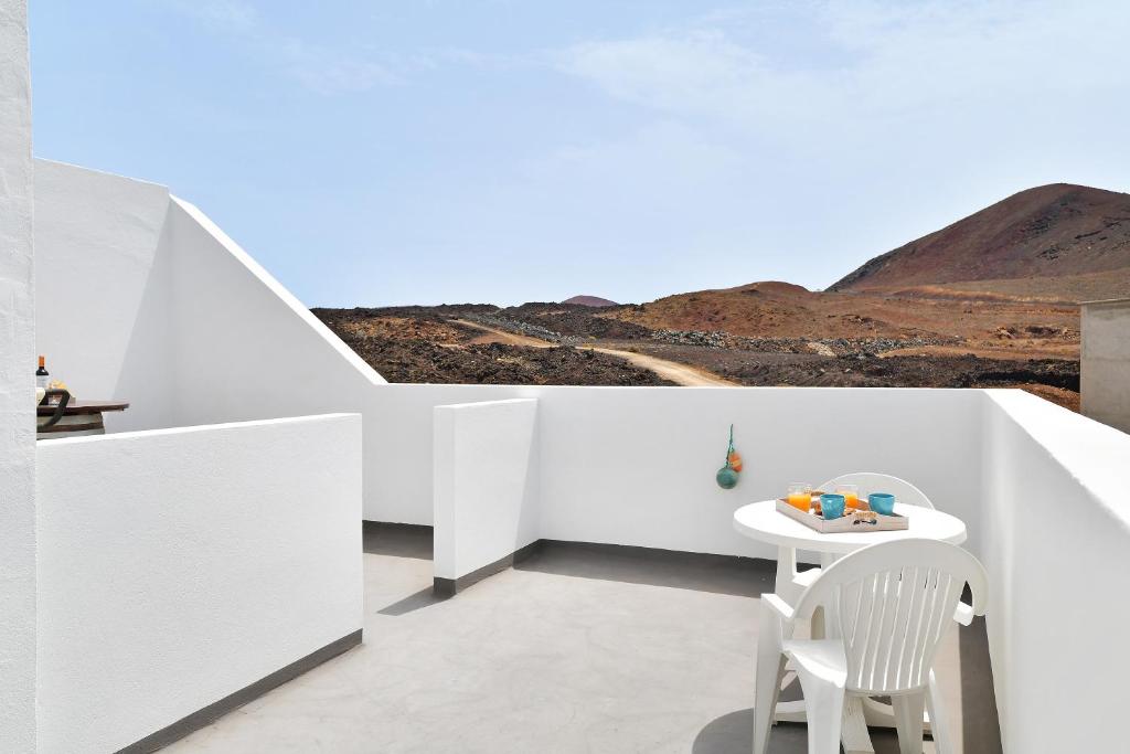 Biały pokój ze stołem, krzesłami i górami w obiekcie Viviendas El Pescador - Timón w mieście El Golfo