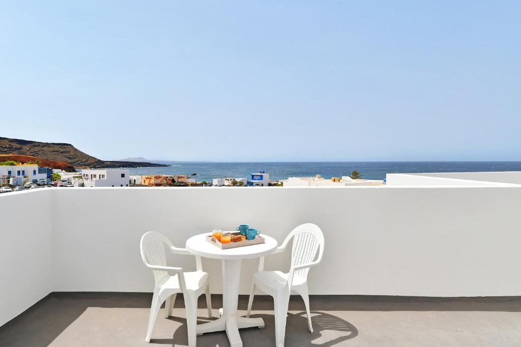 a white table and chairs with a view of the ocean at Viviendas El Pescador - Timón in El Golfo