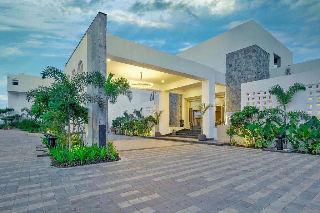 a large white building with a courtyard with plants at Pramod Lands End Resort, a member of Radisson Individuals in Gopālpur