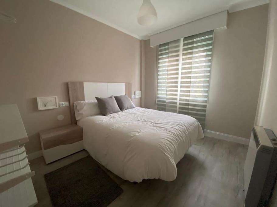 a white bedroom with a large bed and a window at Apartamento Vila de Neda in Neda