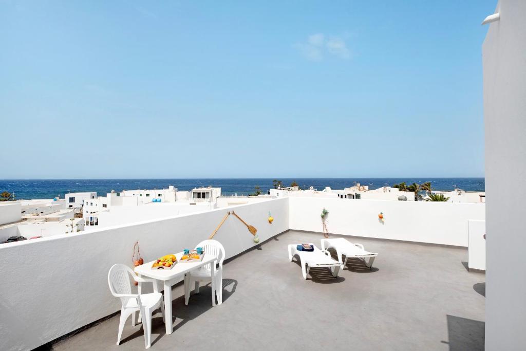 a balcony with white tables and chairs and the ocean at Viviendas El Pescador - Remo in El Golfo