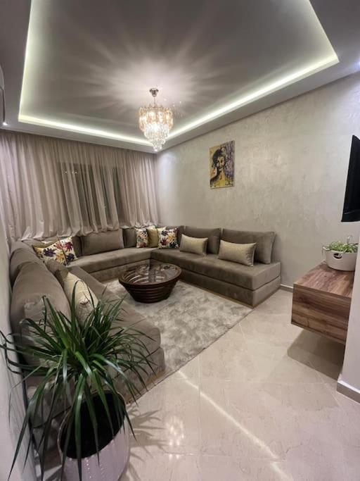 a living room with a couch and a table at bon vivant, calme, famille, équipé, clim, TV, parking, parc, agadir, 7 personnes, stylé, wifi portable in Agadir