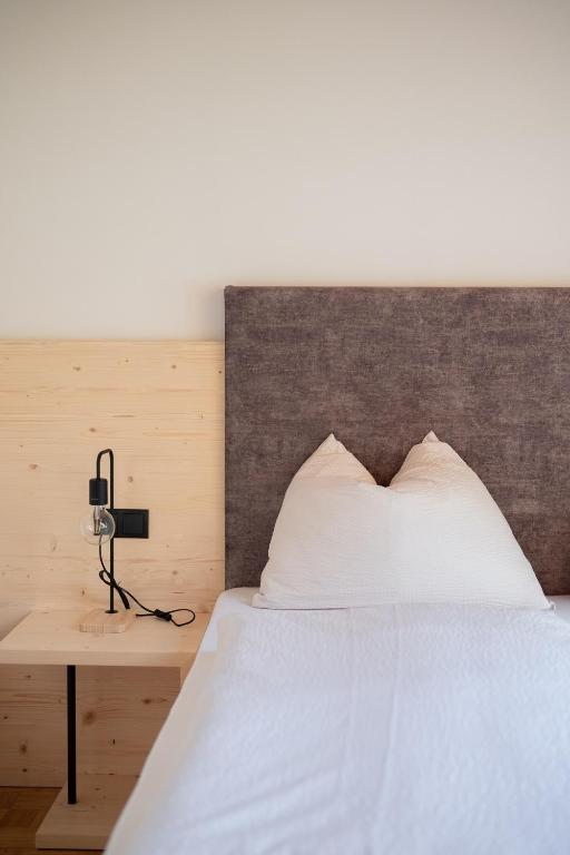 a bedroom with a white bed with a wooden headboard at Töllhof STUDIO mit BAUERNSTUBE in Bressanone