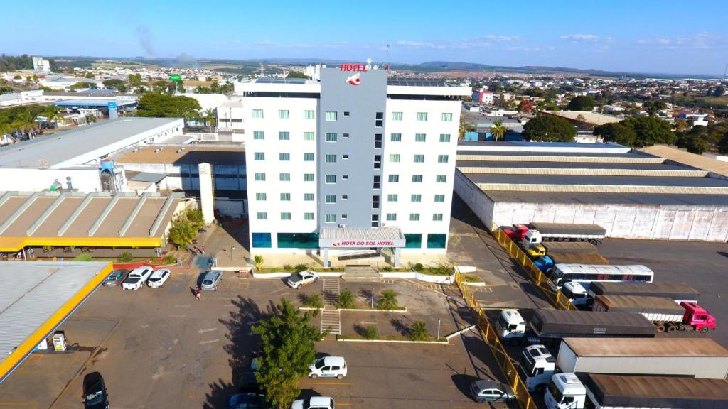 eine Luftansicht auf ein großes weißes Gebäude mit einem Parkplatz in der Unterkunft Hotel Rota Do Sol in Patrocínio
