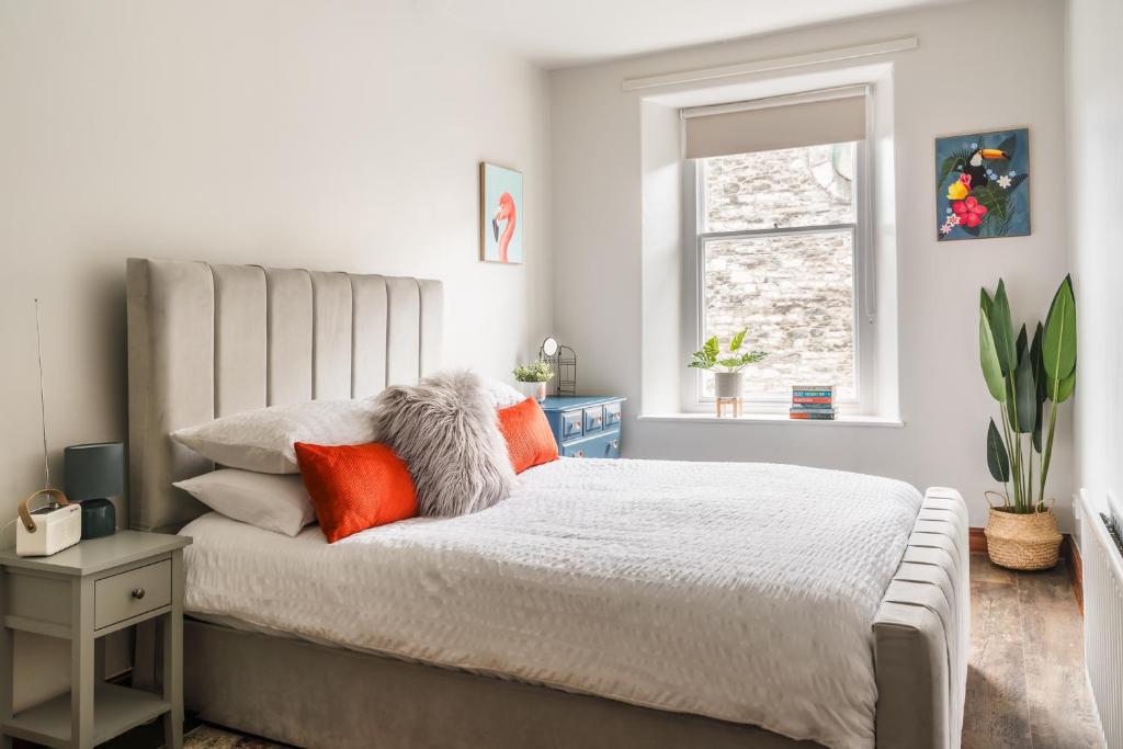 1 dormitorio con 1 cama con almohadas de color naranja y ventana en Doodle Den, en Kendal