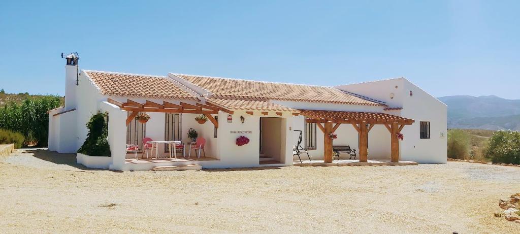 une maison blanche avec une table et des chaises devant elle dans l'établissement 2-Bed Villa with pool garden & parking near Seron, à Serón