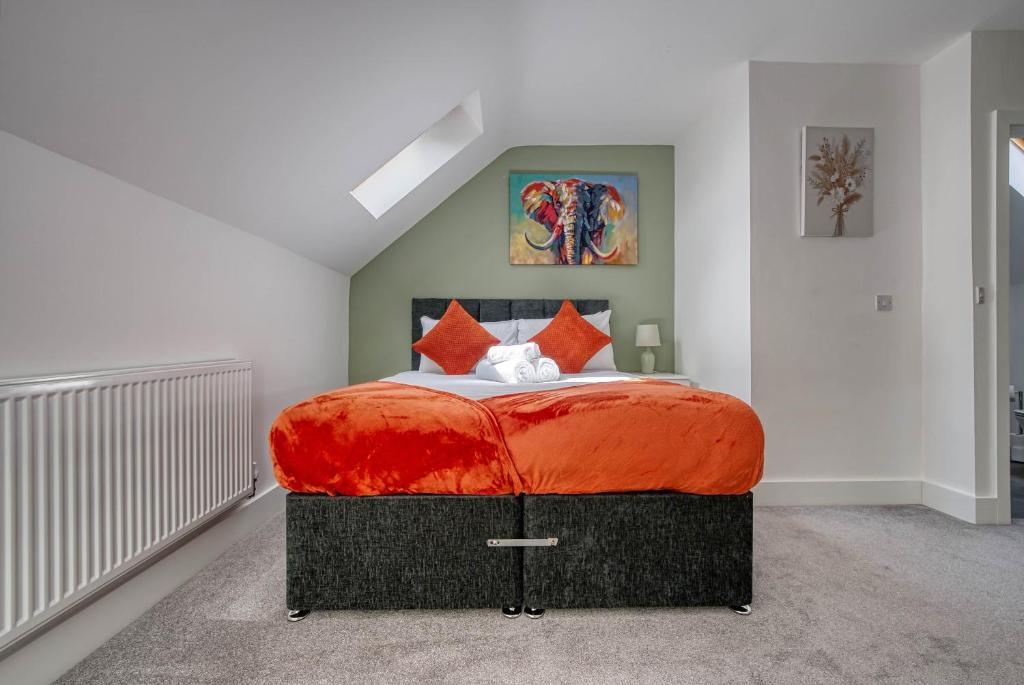 a bedroom with a large bed with an orange blanket at Luxurious Birmingham Home Private Parking WiFi - near to NEC and QEH in Longbridge