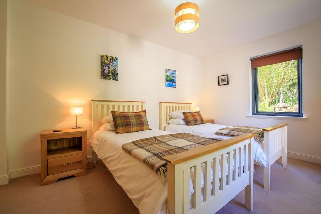 two twin beds in a room with a window at Locholly Lodge in Achiltibuie