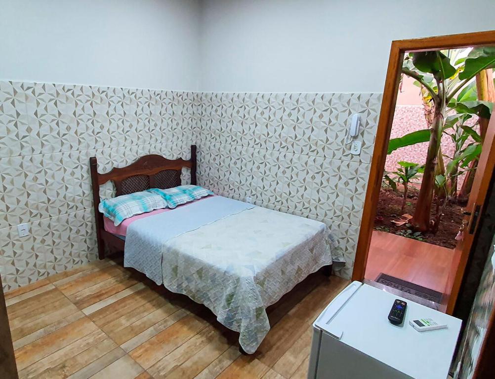 um pequeno quarto com uma cama e um espelho em Casa aconchegante com WiFi Governador Valadares MG em Governador Valadares