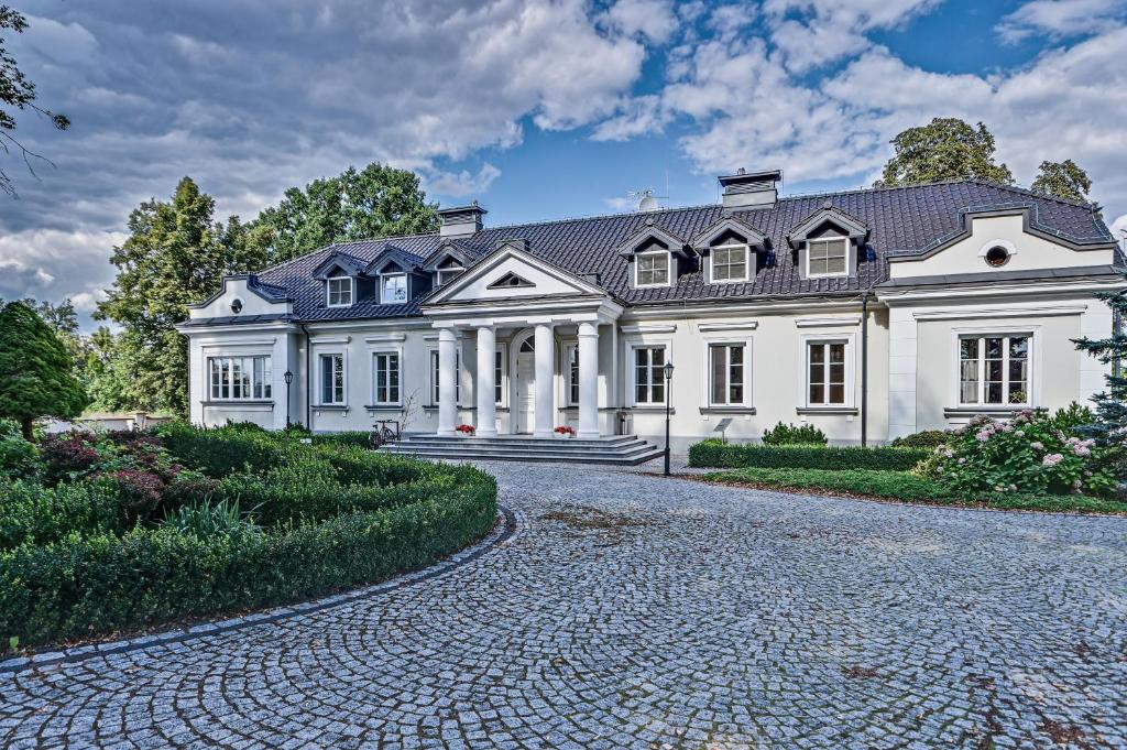 a large white house with a cobblestone driveway at Hotel&SPA Dwór Droblin in Leśna Podlaska