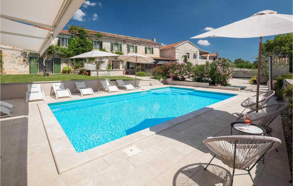einen Pool in einem Garten mit Stühlen und einem Sonnenschirm in der Unterkunft Stunning Home In Tinjan With 4 Bedrooms, Wifi And Outdoor Swimming Pool in Tinjan