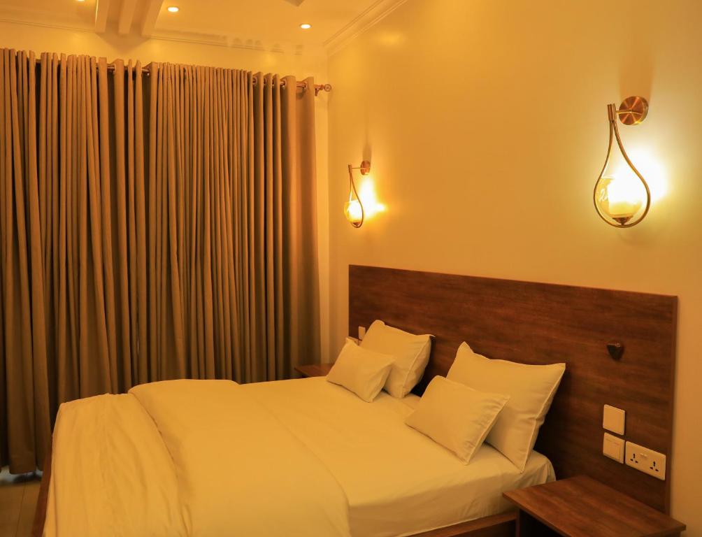 1 dormitorio con 1 cama grande con sábanas y almohadas blancas en ALLY NGALI MOTEL, en Kigali