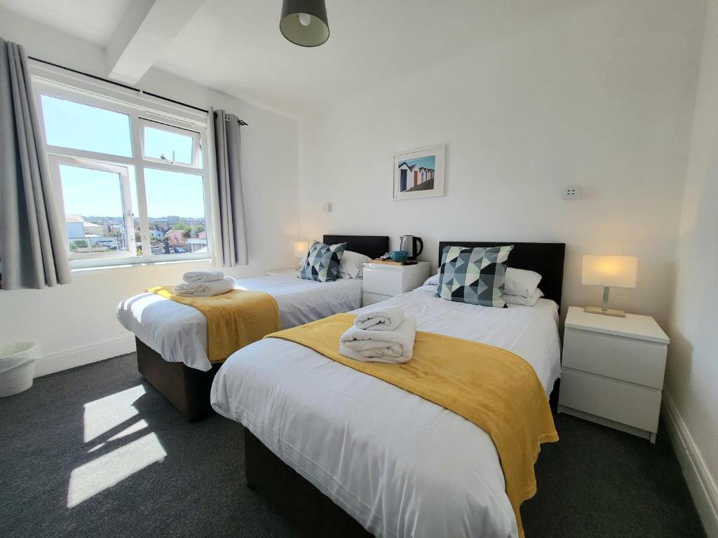 a bedroom with two beds and a window at Beach Hotel Torbay in Paignton