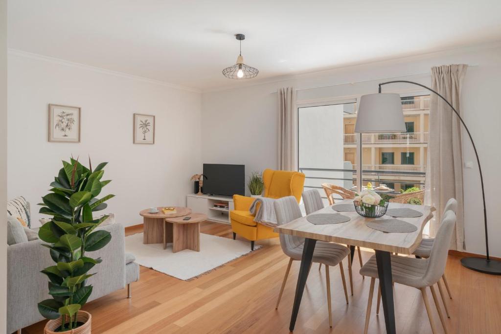 a living room with a dining table and a living room with yellow chairs at On the south coast of the island Ribeira Brava I in Ribeira Brava