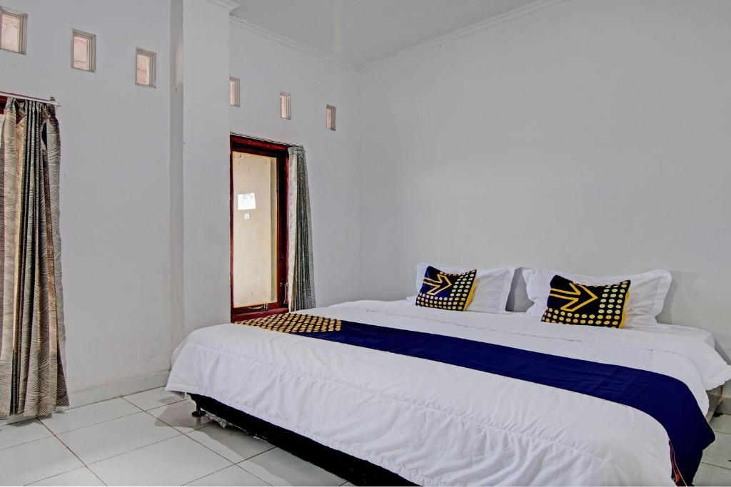 een slaapkamer met een groot bed in een witte kamer bij SPOT ON 92914 Meranti Homestay in Pekanbaru