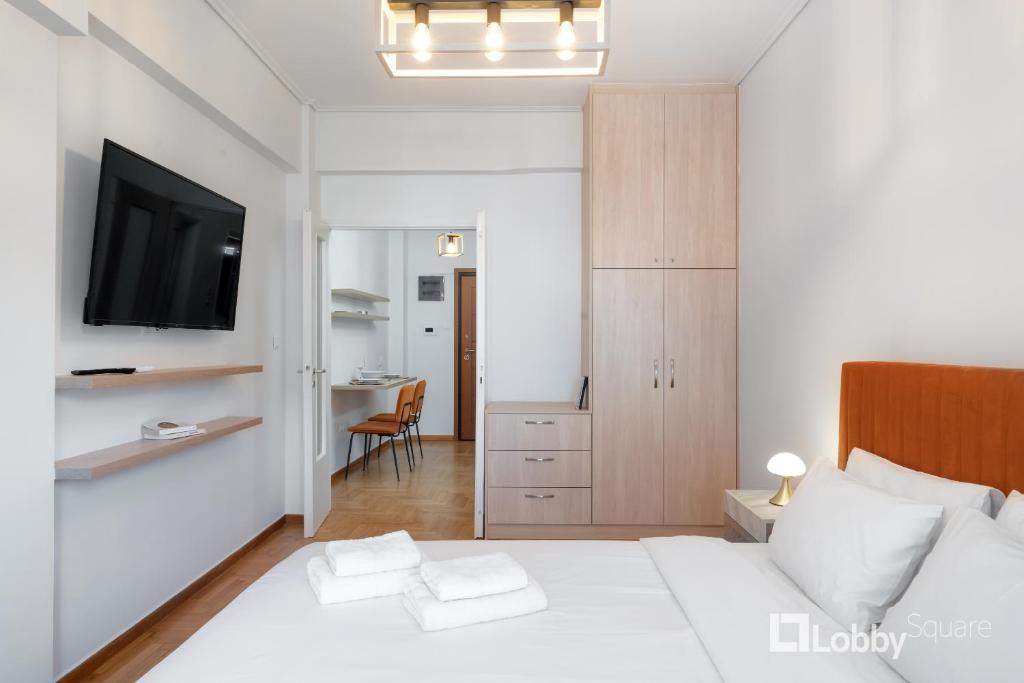 a bedroom with a bed with a television and a desk at Herod Apartment by LobbySquare in Athens