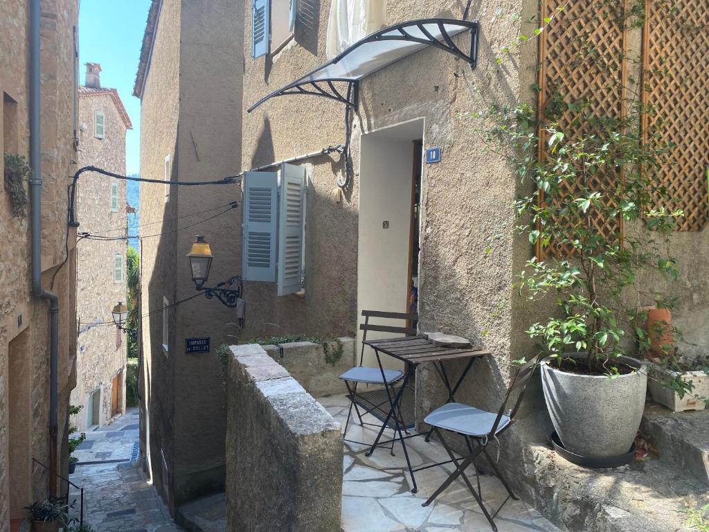 an alley with two chairs and a table in front of a building at Maisonnette au cœur du village in Le Bar-sur-Loup