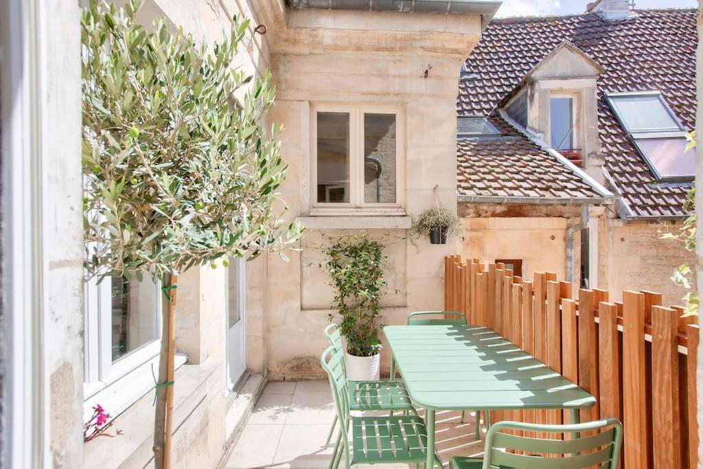 - une table et des chaises vertes sur le balcon d'une maison dans l'établissement Le Matilda - Appt Hypercentre 2 pers, à Caen