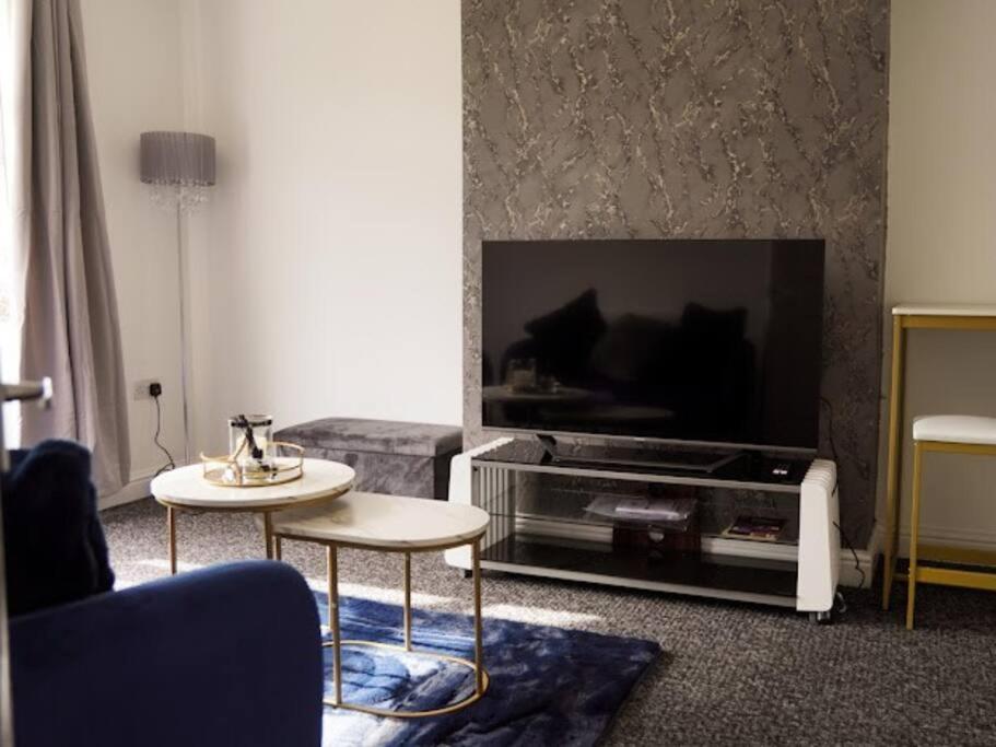 uma sala de estar com uma televisão, um sofá e uma mesa em Home in Speke- 8 mins walk to airport em Speke