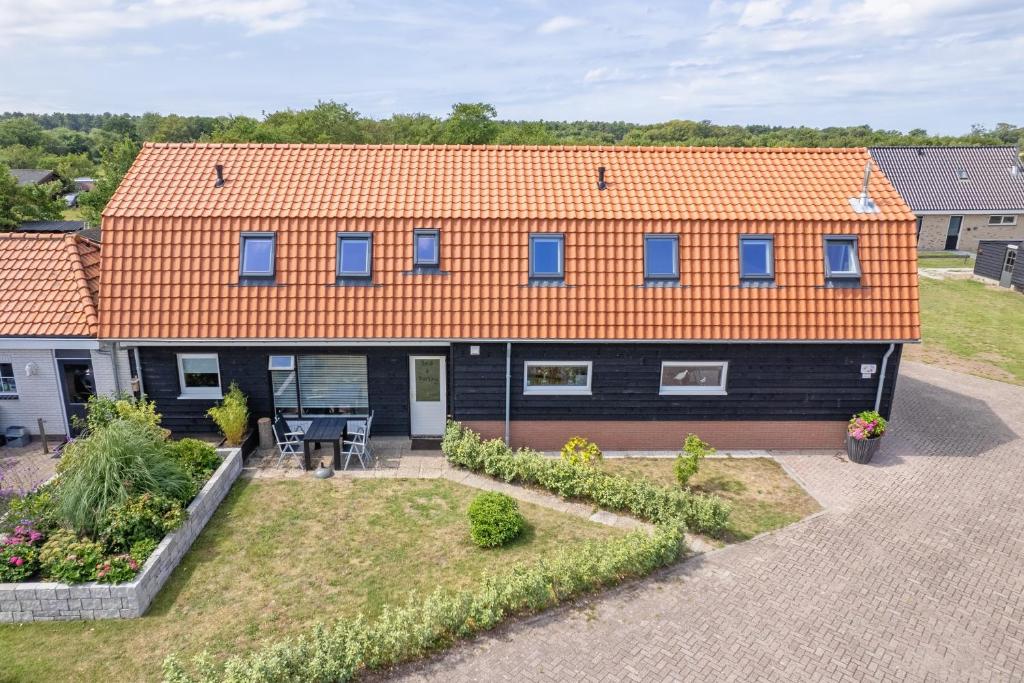 a house with an orange roof and a courtyard at Wulpenweid Bed & Parking in Den Burg