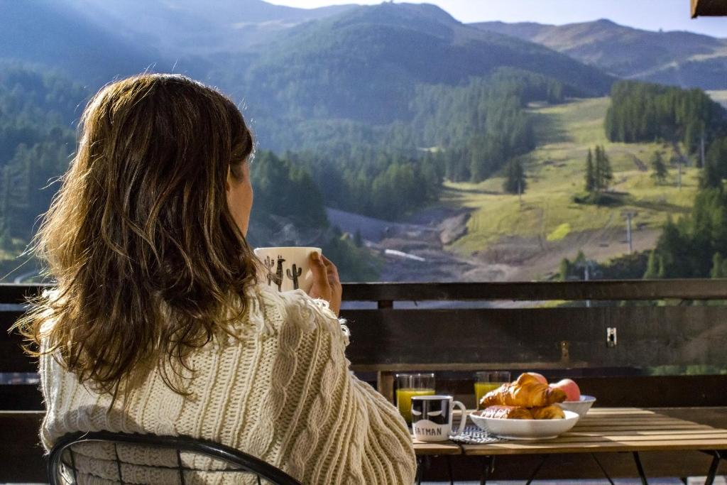 una mujer sentada en una mesa con un tazón de comida en Studio Cocon aux Orres 1650 au pied des pistes et vue montagne, en Les Orres