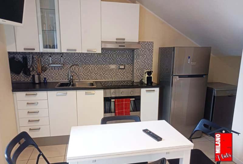 a kitchen with a white table and a refrigerator at MilanoFlats - bilocale BrandaCastiglioni in Milan