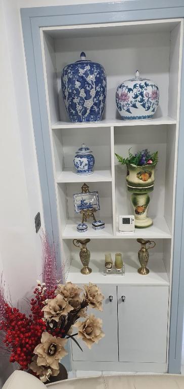 une étagère blanche remplie de plaques et de vases bleus et blancs dans l'établissement Min Su Rooms, à Stanwell