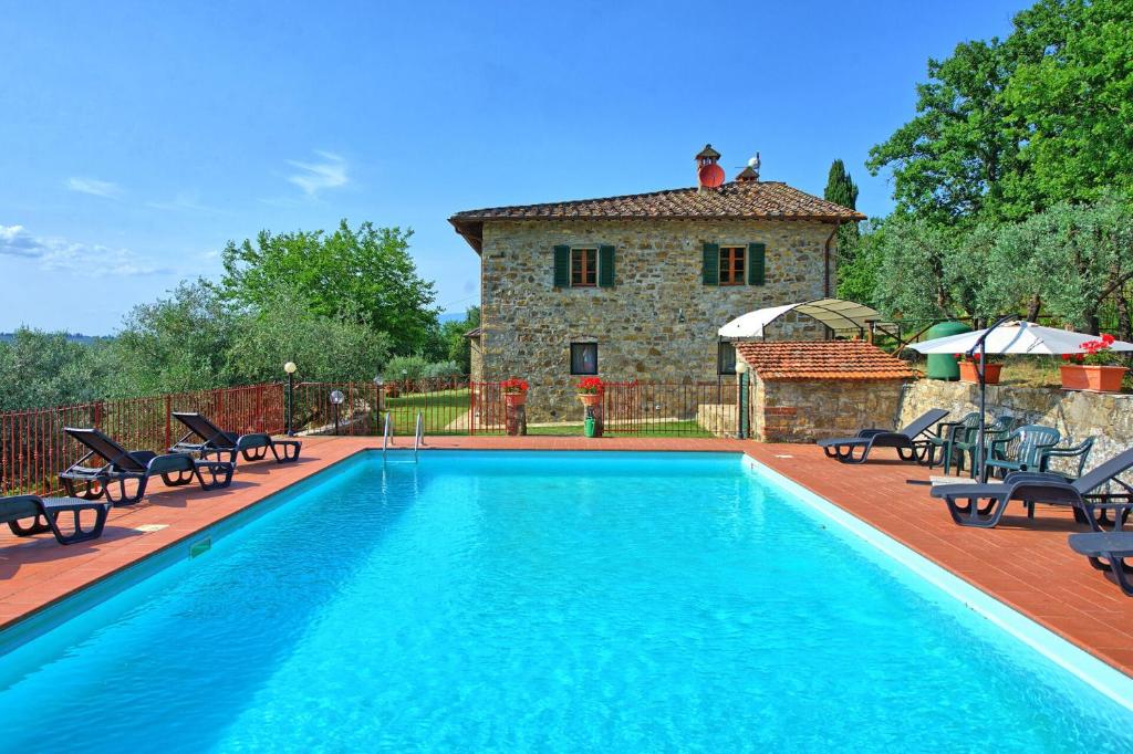 uma piscina com cadeiras e uma casa ao fundo em Querciolaia by PosarelliVillas em Pieve a Presciano