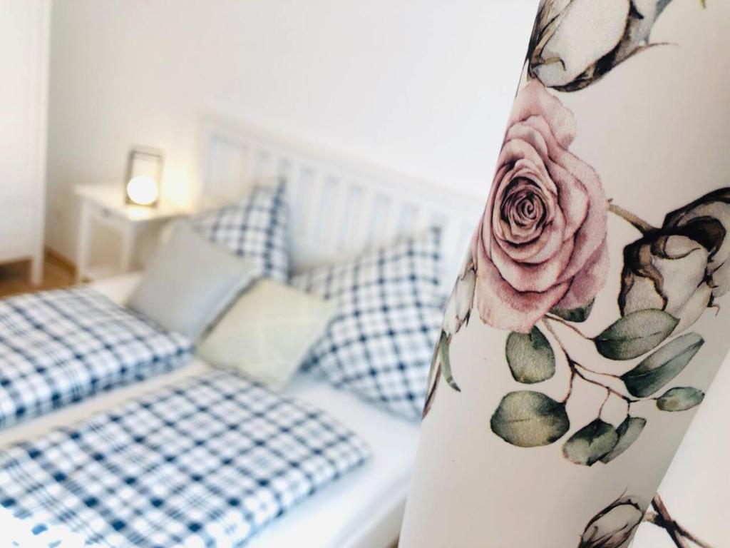 a vase with a rose on it next to a bed at Haus Gerda Ferienwohnung 2 in Arnbruck