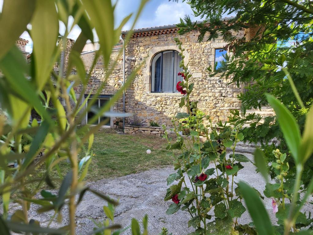 una casa in pietra con finestra e alcune piante di La Grange 1832 - A 10 mins d'Aubenas a Saint-Étienne-de-Boulogne