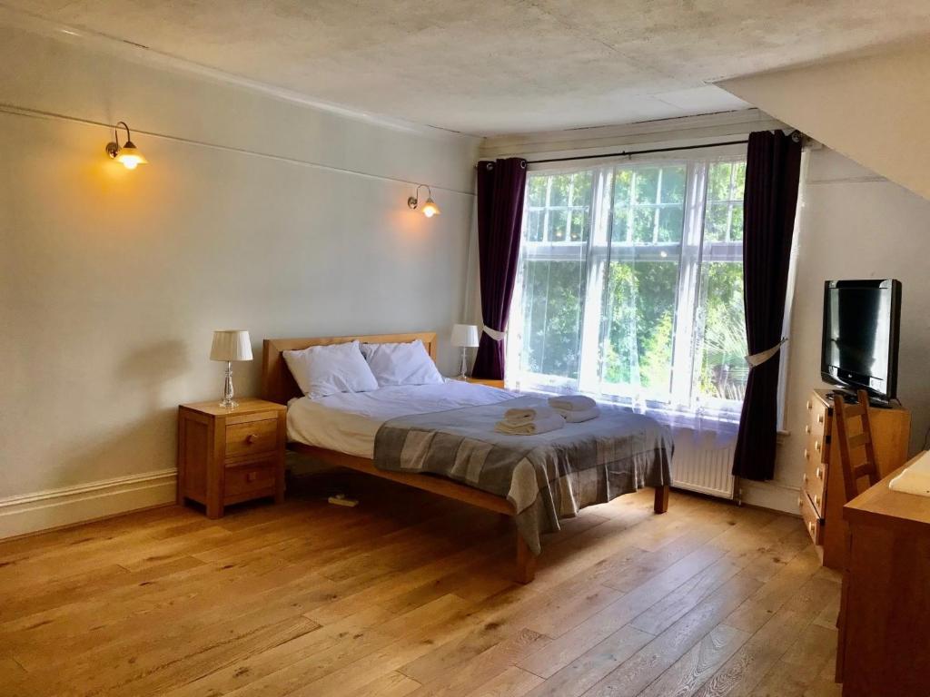 um quarto com uma cama e uma grande janela em Spacious 3 Bed Room Flat in South West London em Londres