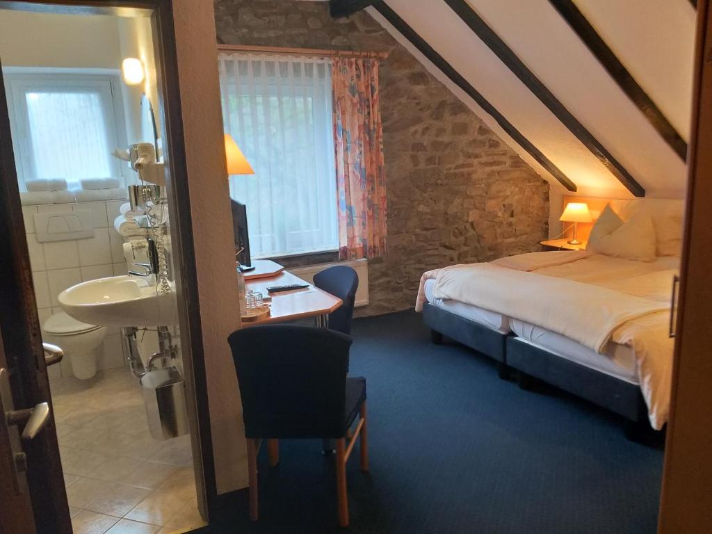 um quarto com uma cama, uma secretária e um lavatório. em Hotel Klinger em Plettenberg