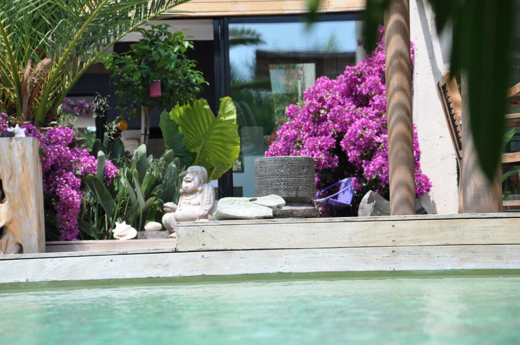 a garden with purple flowers and a statue next to the water at Villa Bali in Cassis