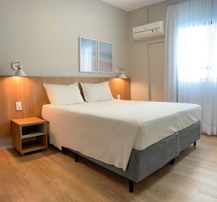 een groot wit bed in een kamer met een raam bij Hotel Italia in Balneário Camboriú