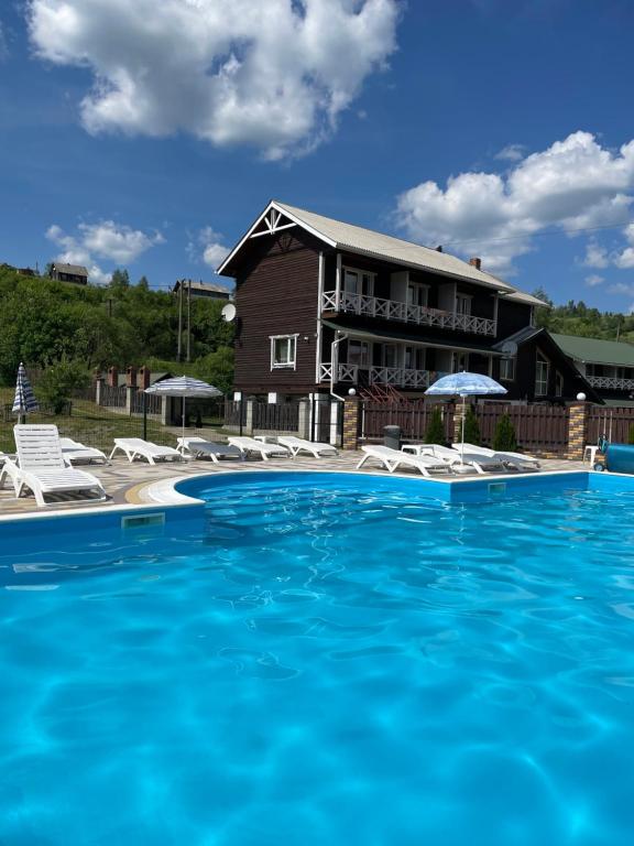 a swimming pool with chairs and a house at Zarichna Lyks in Slavske
