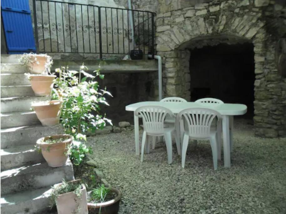 une table blanche et deux chaises dans la cour dans l'établissement Charming village house 2/4 travelers, à Dieulefit