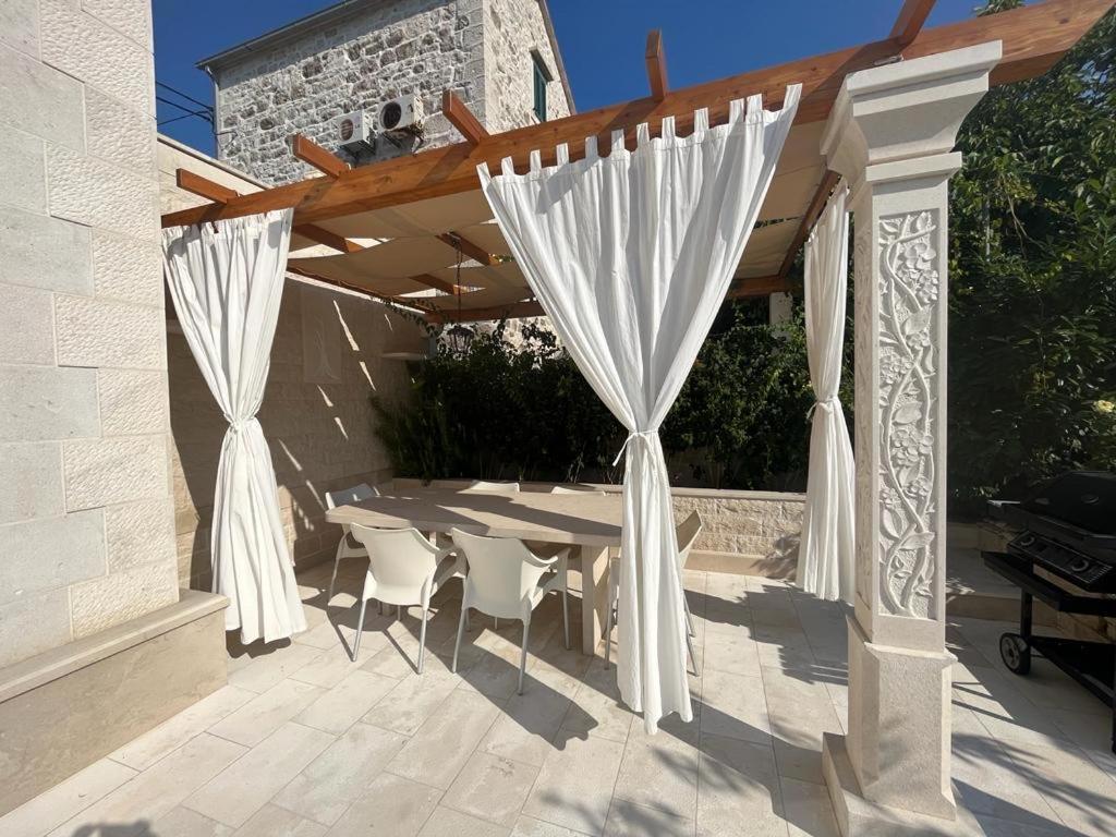 a patio with a table and white curtains at BUKY HOUSE in Sumartin