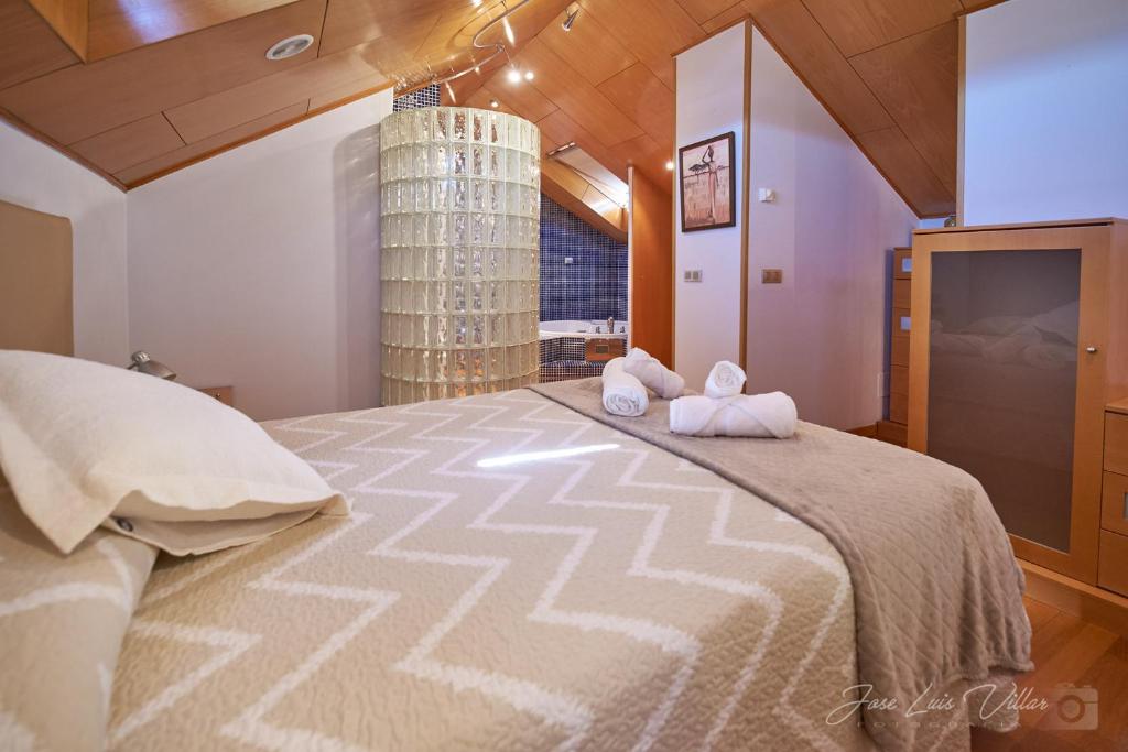 een slaapkamer met een groot bed en handdoeken bij Duplex Monforte in Monforte de Lemos