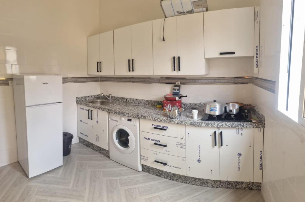 a kitchen with white cabinets and a washing machine at Familie appartement Alhoceima in Ajdir