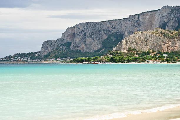 Blick auf einen Strand mit einem Berg im Hintergrund in der Unterkunft Il Gelsomino in Palermo