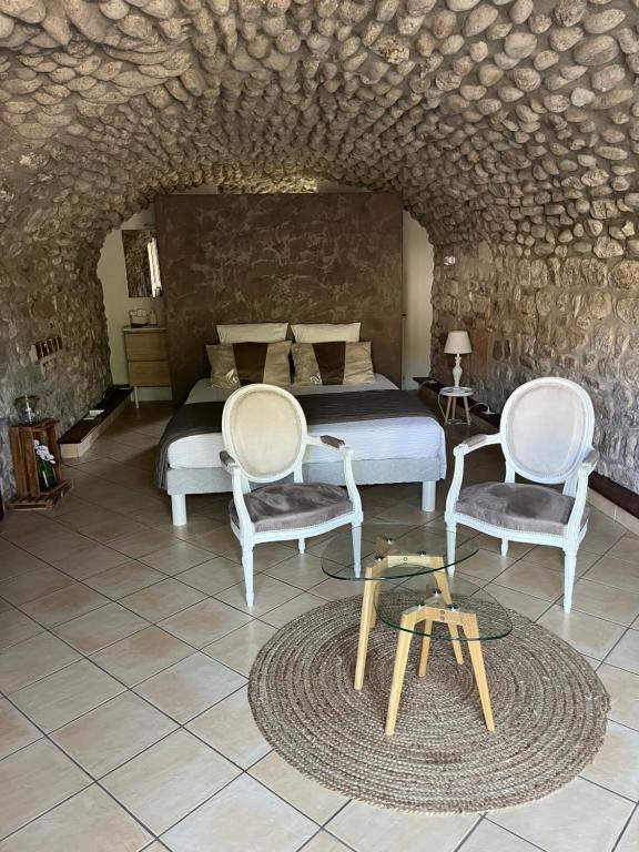 sypialnia z łóżkiem, 2 krzesłami i stołem w obiekcie GITE DE LA CAPPELLA - CHAMBRE D'HÔTES A VOLTA w mieście Aubenas