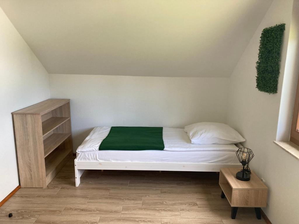 a bedroom with a white bed with a green blanket at Domki Wypoczynkowe LUBKOWIA in Lubkowo