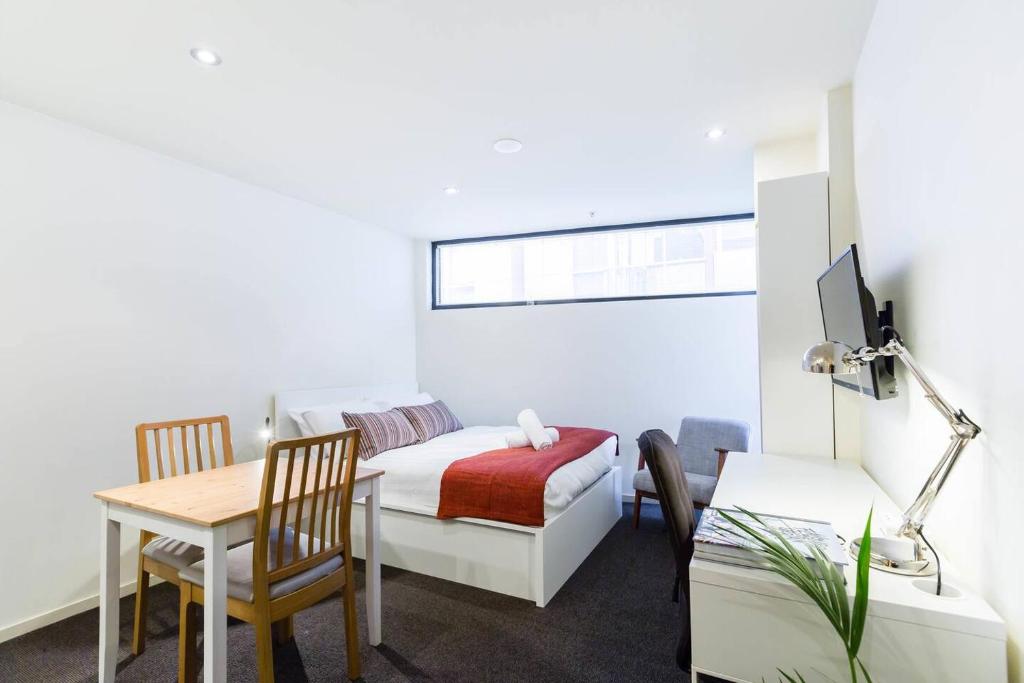 ein Schlafzimmer mit einem Bett, einem Schreibtisch und einem Tisch in der Unterkunft Simple on Swanston - A Central Student Accom Studio in Melbourne