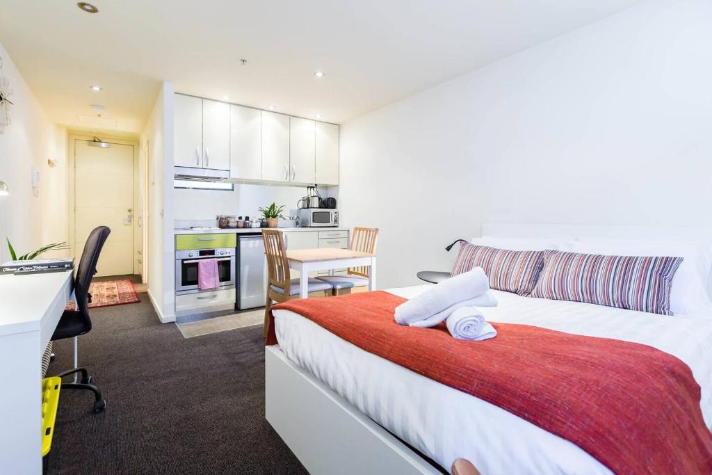 1 Schlafzimmer mit einem großen Bett und einer Küche in der Unterkunft Simple on Swanston - A Central Student Accom Studio in Melbourne